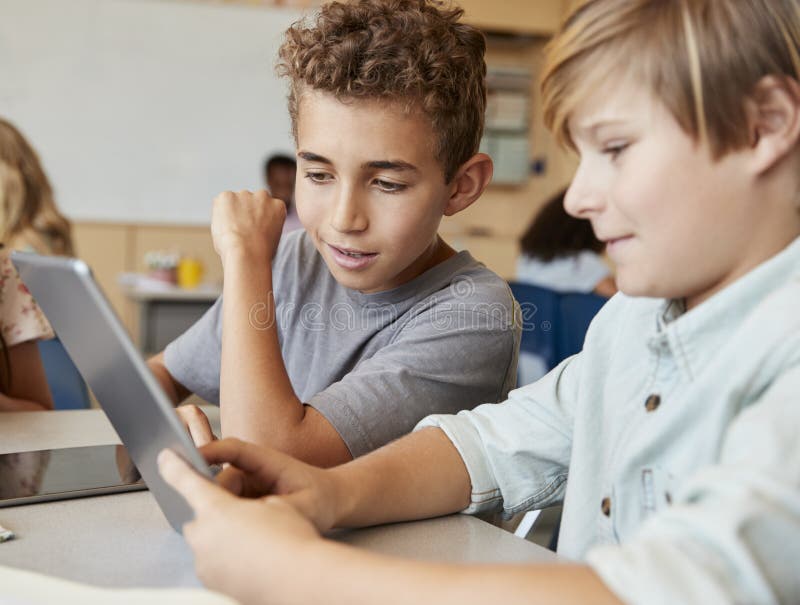 Schoolboys working together with tablet computer, close up