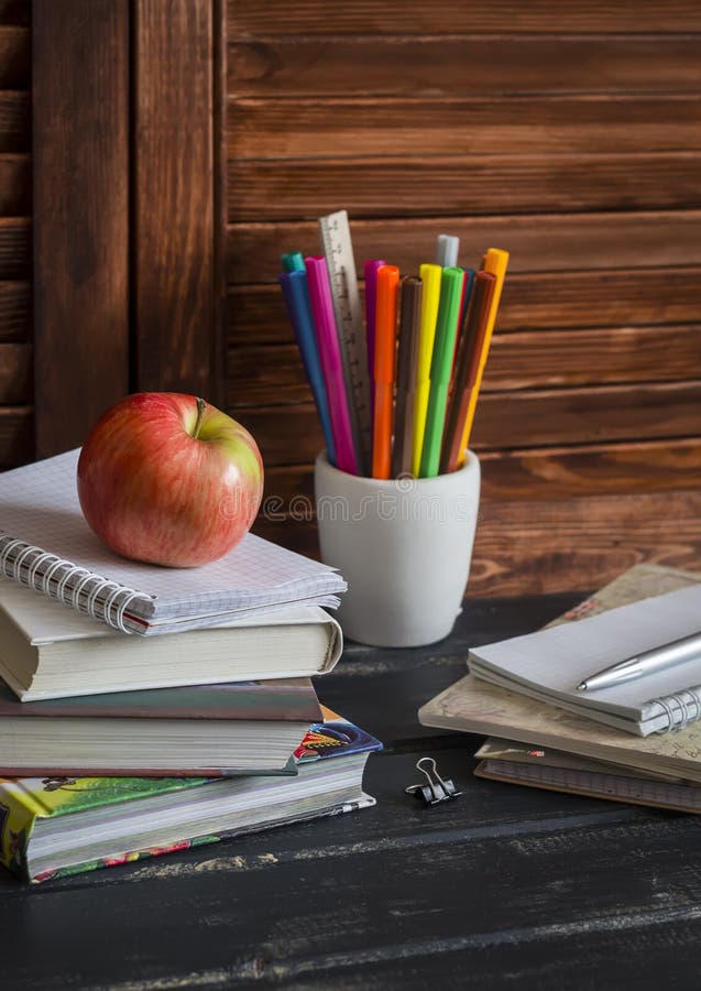 Schoolchild and student studies accessories. Books, notebooks, notepads, colored pencils, pens, rulers and a fresh red apple. Home
