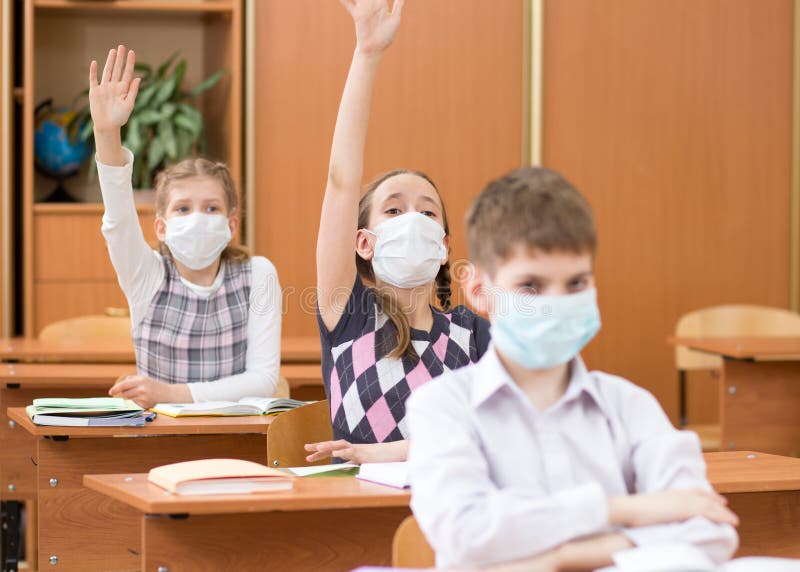 Schoolers wearing protection mask to prevent virus on lesson in classroom