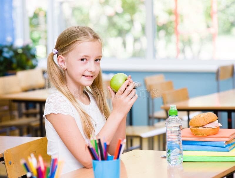 Schoolgirl with apple while having lunch stock image