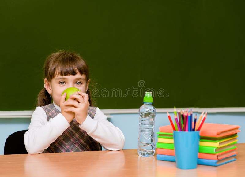 Schoolgirl with apple near chalkboard stock image