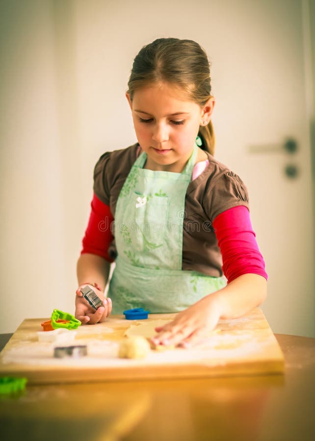 Chica de escuela horneando galletas.