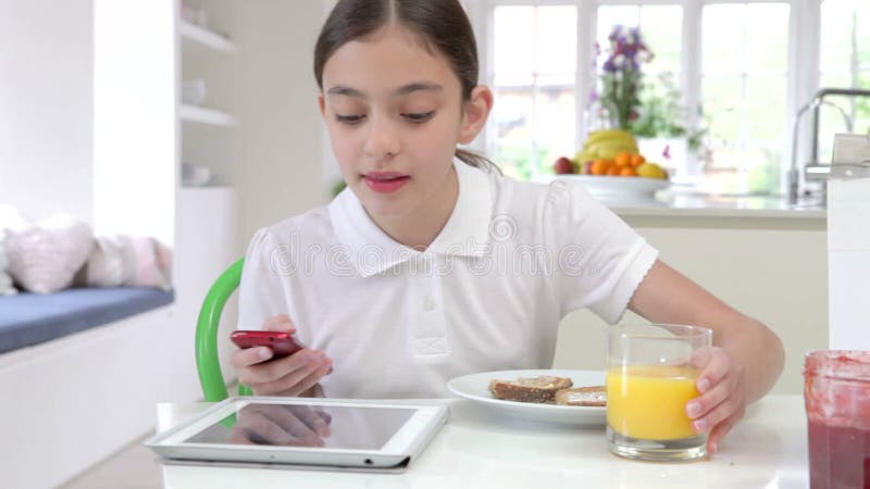 Schoolgirl With Digital Tablet And Mobile Eating Toast