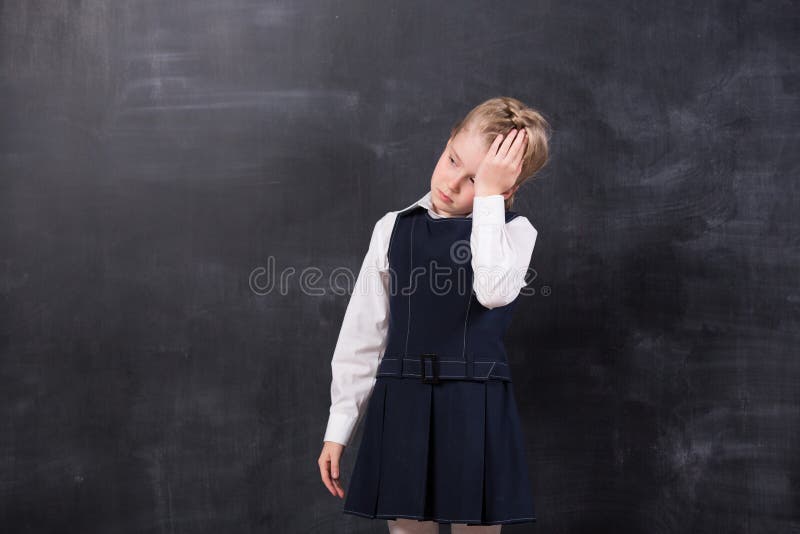 Schoolgirl with headache stands at the blackboard