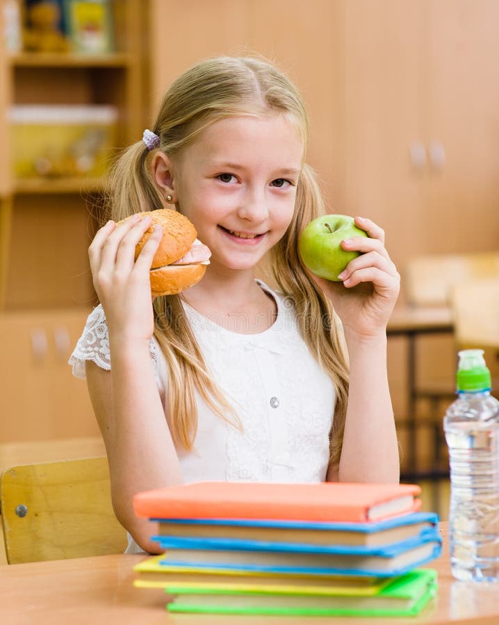 Schoolgirl holding an apple and fast food stock image