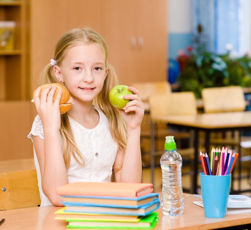 Schoolgirl holding an apple and fast food royalty free stock photography