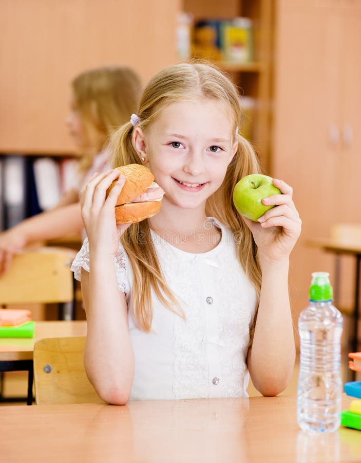 Schoolgirl holding an apple and fast food royalty free stock photos