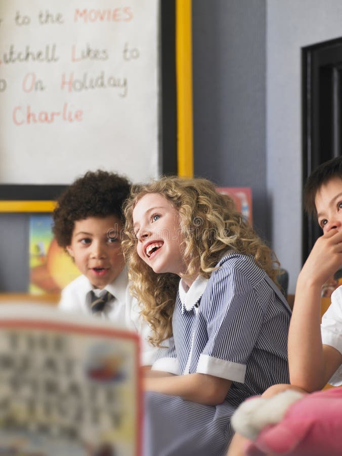 Cheerful elementary schoolgirl with boys sitting in classroom. Cheerful elementary schoolgirl with boys sitting in classroom