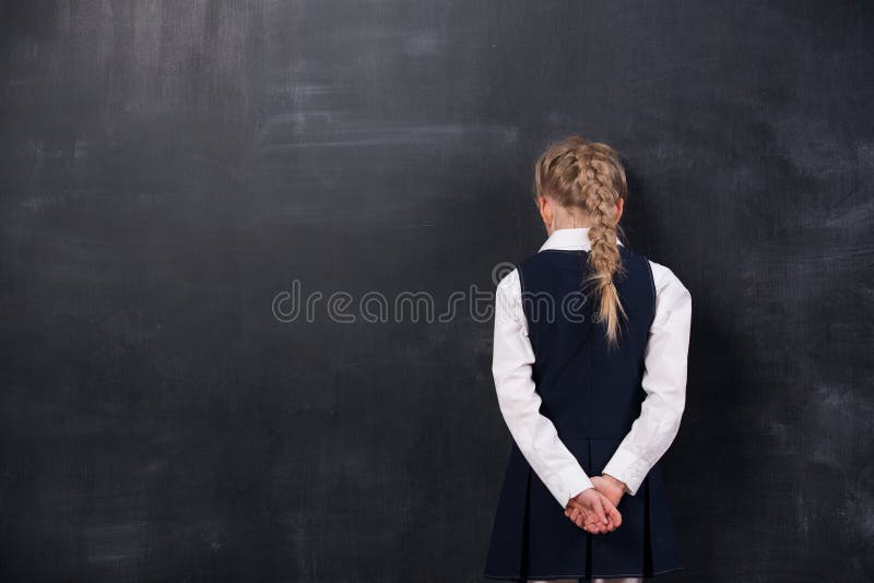 Schoolgirl leaning her forehead against blackboard