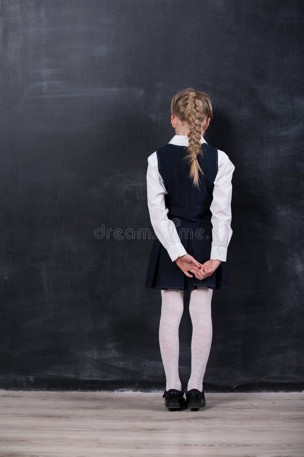 Schoolgirl leaning her forehead against blackboard