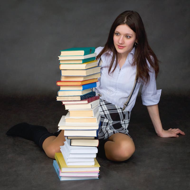 Schoolgirl looks at huge pile of textbooks