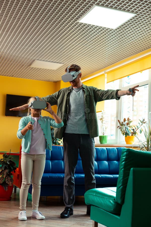 Schoolgirl playing in virtual reality with her teacher. stock images