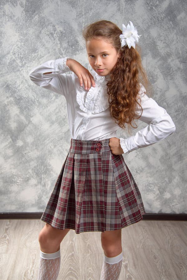 The Schoolgirl in School Uniform Poses and Has Fun on a Light Gray ...