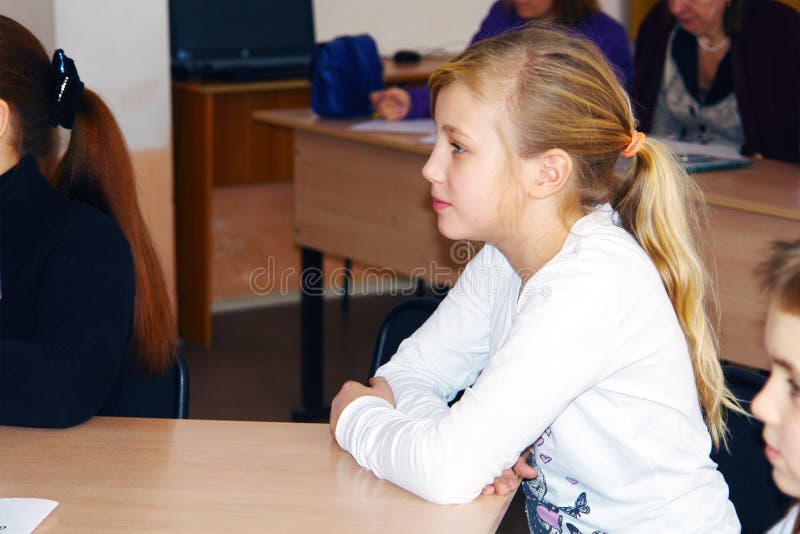 CHAPAEVSK, SAMARA REGION, RUSSIA - DECEMBER 07, 2017: Grammar school in city Chapaevsk. Schoolgirl with blond hair and in a white blouse sitting at the Desk in the classroom. SOFT FOCUS. CHAPAEVSK, SAMARA REGION, RUSSIA - DECEMBER 07, 2017: Grammar school in city Chapaevsk. Schoolgirl with blond hair and in a white blouse sitting at the Desk in the classroom. SOFT FOCUS