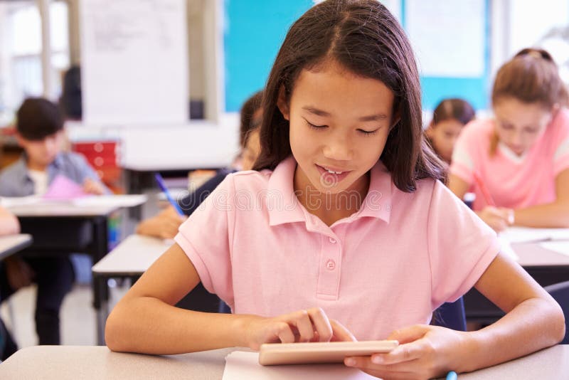Schoolgirl using tablet computer in elementary school class royalty free stock images