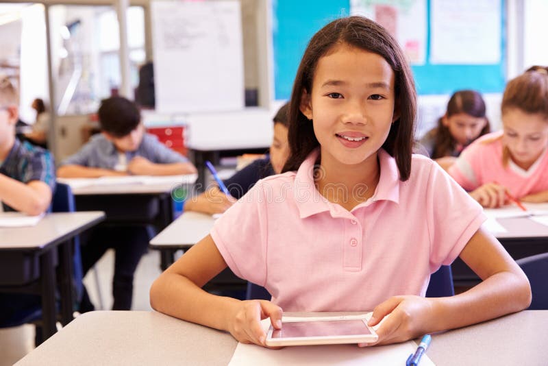 Schoolgirl using tablet computer in elementary school class stock image