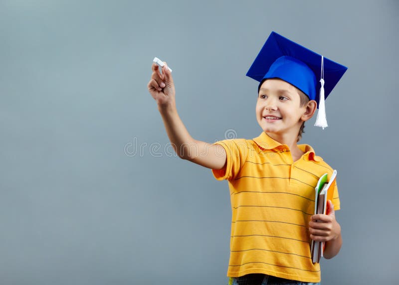 Portrait of cute schoolkid writing with chalk on imaginary blackboard