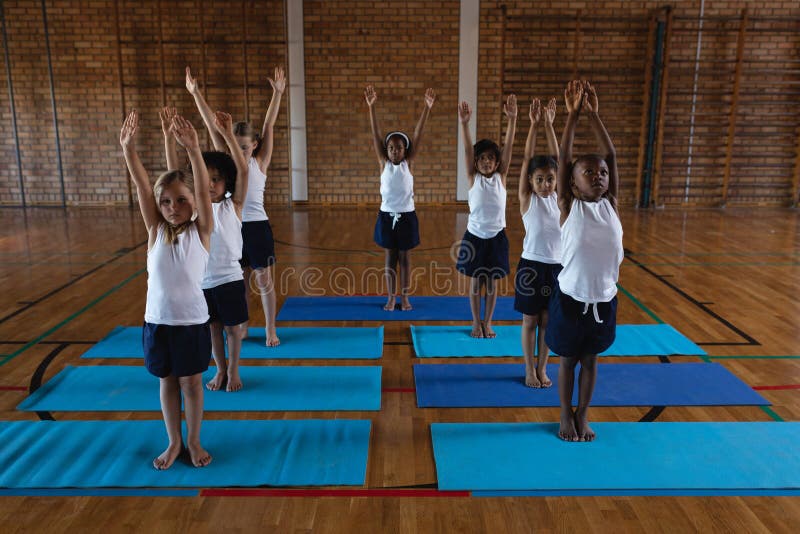 Schoolkids Doing Yoga and Meditating on a Yoga Mat in School Stock