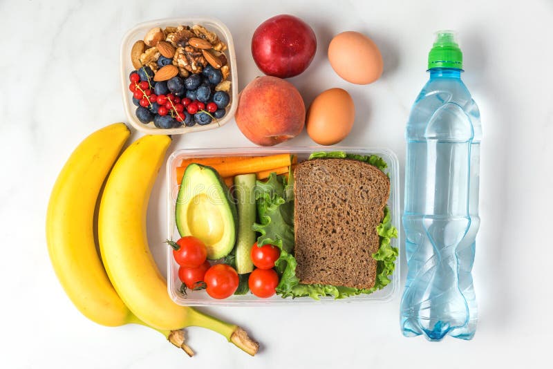 Schoolmaaltijddozen met sandwich, groenten, noten, bessen, banaan, eieren, perziken en water op witte marmeren achtergrond royalty-vrije stock afbeelding Schoolmaaltijddozen met sandwich, groenten, noten, bessen, banaan, eieren, perziken en water op witte marmeren achtergrond royalty-vrije stock afbeelding