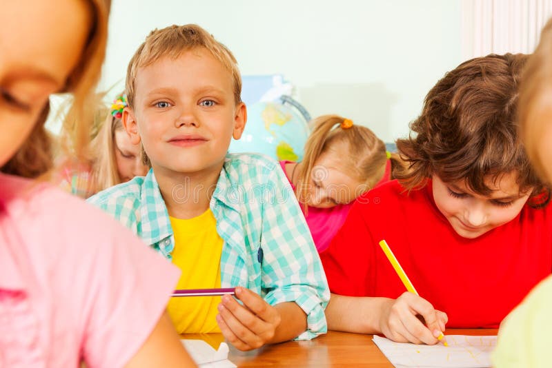 Schoolmates sit together in classroom and write royalty free stock images