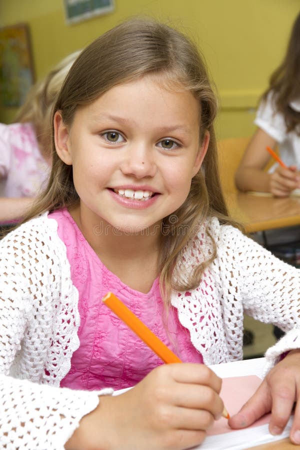 Schoolgirl in a classroom is looking to camera. Schoolgirl in a classroom is looking to camera.