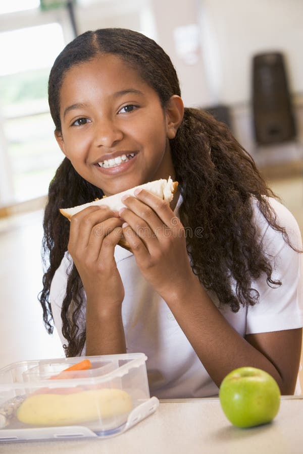 Schoolmeisje dat van haar lunch in schoolcafetaria geniet