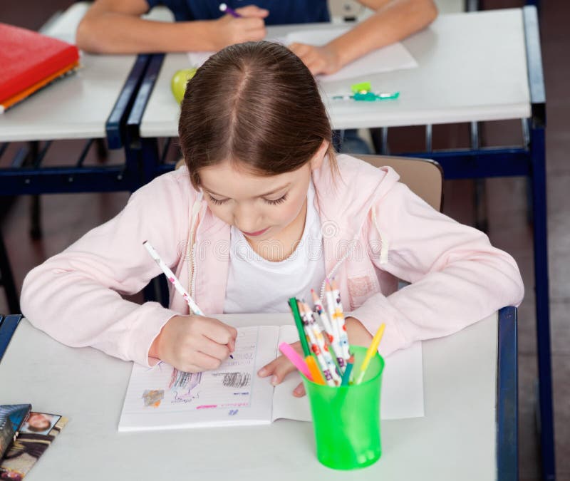 Schoolmeisjetekening bij Bureau in Klaslokaal royalty-vrije stock afbeelding Schoolmeisjetekening bij Bureau in Klaslokaal royalty-vrije stock afbeelding