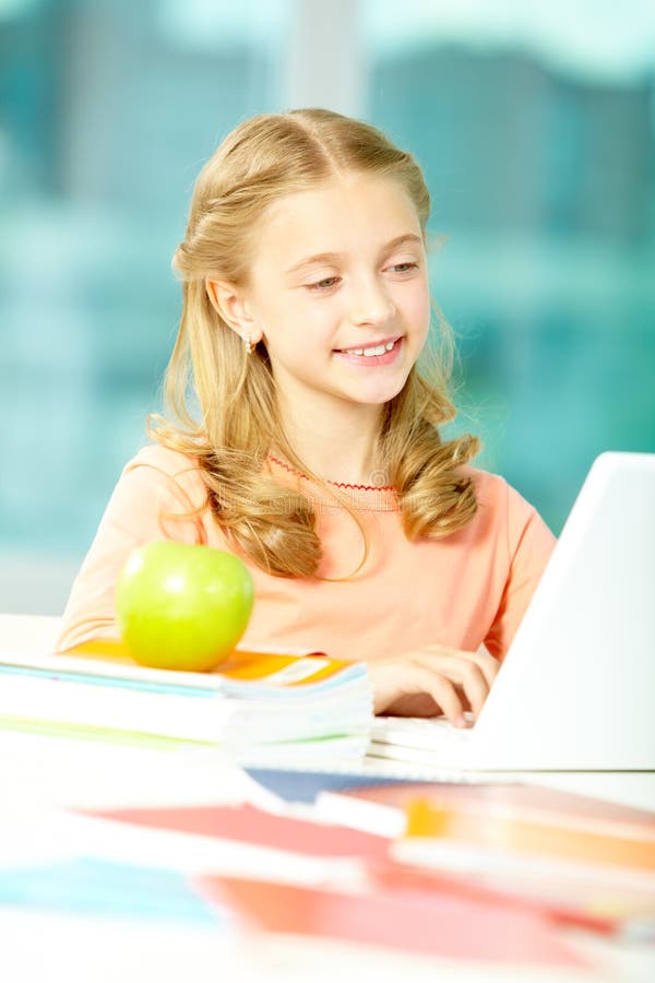 Portrait of smart schoolgirl sitting in classroom and typing. Portrait of smart schoolgirl sitting in classroom and typing