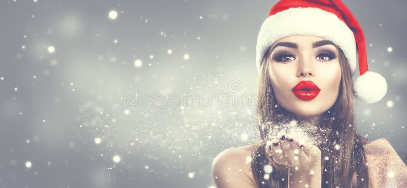 Schoonheids modelvrouw in de hoeden blazende sneeuw van de Kerstman in haar hand De maniermeisje van de Kerstmiswinter op vakanti royalty-vrije stock fotografie Schoonheids modelvrouw in de hoeden blazende sneeuw van de Kerstman in haar hand De maniermeisje van de Kerstmiswinter op vakanti royalty-vrije stock fotografie
