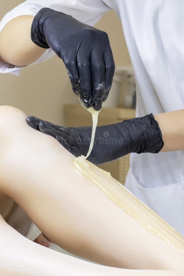 Schoonheidsspecialist die de benen van de vrouw met vloeibare suiker in kuuroordcentrum ontharen Ontharing van benen met suikerde royalty-vrije stock fotografie Schoonheidsspecialist die de benen van de vrouw met vloeibare suiker in kuuroordcentrum ontharen Ontharing van benen met suikerde royalty-vrije stock fotografie