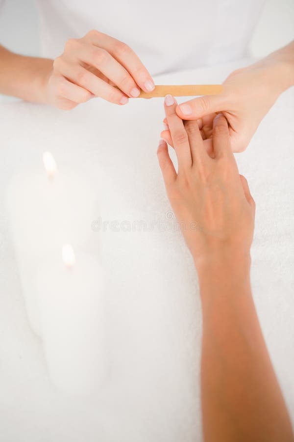 Schoonheidsspecialist die vrouwelijke cliëntenspijkers indienen bij de salon van de kuuroordschoonheid royalty-vrije stock afbeelding Schoonheidsspecialist die vrouwelijke cliëntenspijkers indienen bij de salon van de kuuroordschoonheid royalty-vrije stock afbeelding