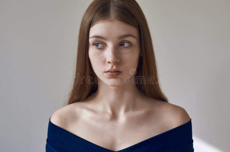 Schoonheidsthema: portret van een mooi jong meisje met sproeten op haar gezicht en het dragen van een blauwe kleding op een witte royalty-vrije stock foto Schoonheidsthema: portret van een mooi jong meisje met sproeten op haar gezicht en het dragen van een blauwe kleding op een witte royalty-vrije stock foto