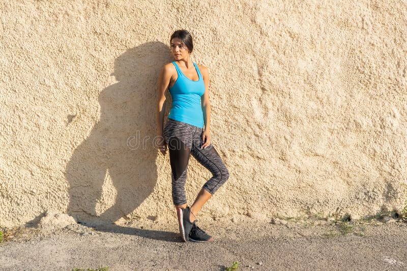 Schot die van geschikte agent tegen een muur zich in openlucht bevinden Het sportieve vrouw ontspannen na het runnen van oefening royalty-vrije stock foto Schot die van geschikte agent tegen een muur zich in openlucht bevinden Het sportieve vrouw ontspannen na het runnen van oefening royalty-vrije stock foto