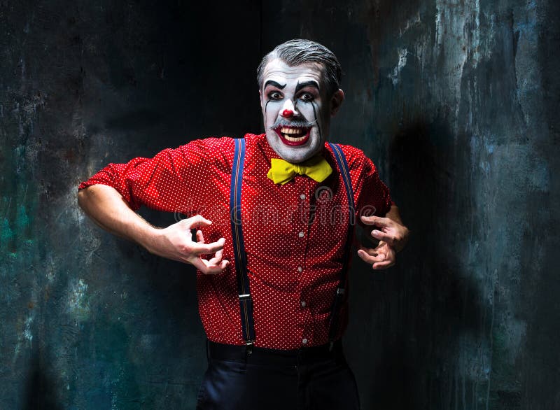 Schrecklicher Clown und Halloween-Thema: Verrückter roter Clown in einem Hemd mit Hosenträgern stockfotografie Schrecklicher Clown und Halloween-Thema: Verrückter roter Clown in einem Hemd mit Hosenträgern stockfotografie