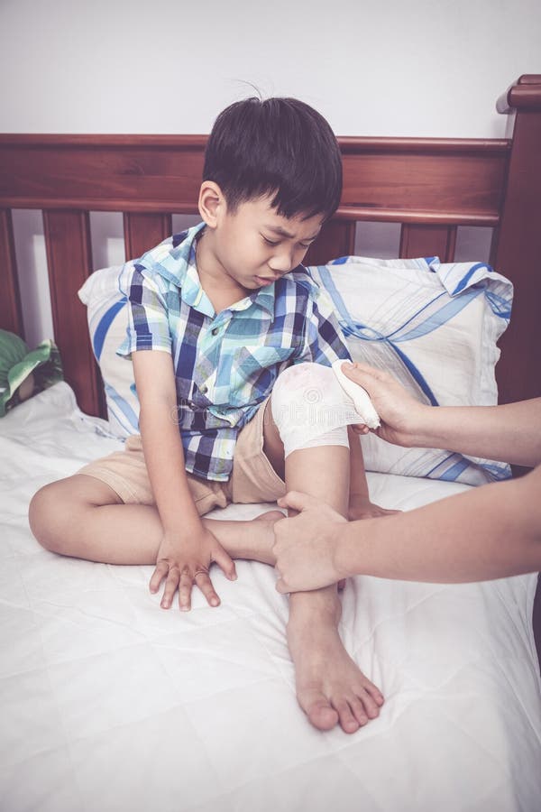 Schreeuwend verwond kind Moeder die zoons` s knie verbinden Uitstekende toon stock foto Schreeuwend verwond kind Moeder die zoons` s knie verbinden Uitstekende toon stock foto