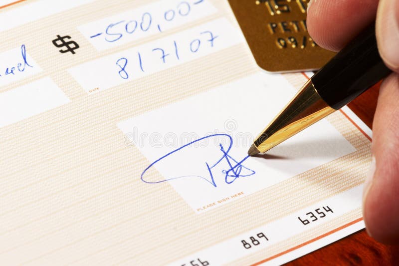 Writing a bank check with a ball pen, gold card in background *** Note: check, numbers and signature are fictitious!. Writing a bank check with a ball pen, gold card in background *** Note: check, numbers and signature are fictitious!