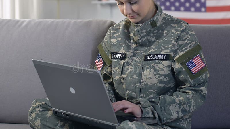 Schreibenlaptop der amerikanischen Militärangehörigen und Lächeln auf der Kamera, Informationen suchend