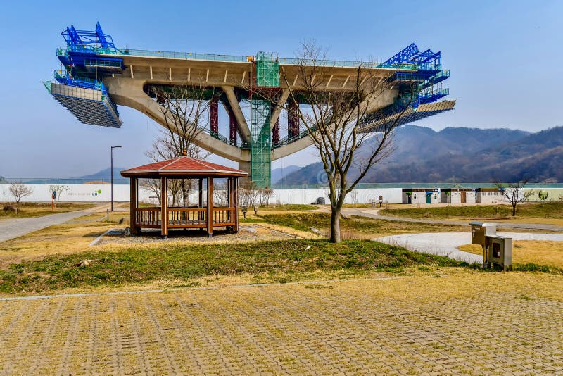 Sejong, South Korea; April 1, 2020: Picnic shelter in front of section of new bridge under construction in rural public park. Sejong, South Korea; April 1, 2020: Picnic shelter in front of section of new bridge under construction in rural public park