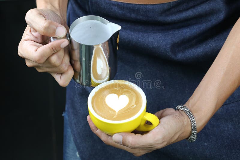 Schuim van de Barista het gietende melk voor het maken van koffie latte tot kunst met patroon het hart in een kop