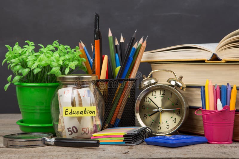 Schulbedarf und Glasgef?? mit Geld f?r Bildung auf Holztisch lizenzfreie stockfotografie Schulbedarf und Glasgef?? mit Geld f?r Bildung auf Holztisch lizenzfreie stockfotografie