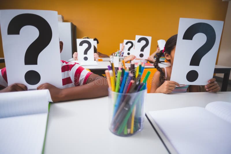 Schulen Sie die Kinder, die ihr Gesicht mit Fragezeichenzeichen bedecken stockbild Schulen Sie die Kinder, die ihr Gesicht mit Fragezeichenzeichen bedecken stockbild