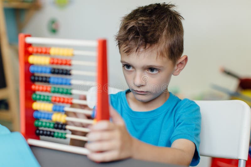 Schuljunge, der Mathe mit einem Abakus lernt lizenzfreie stockfotografie