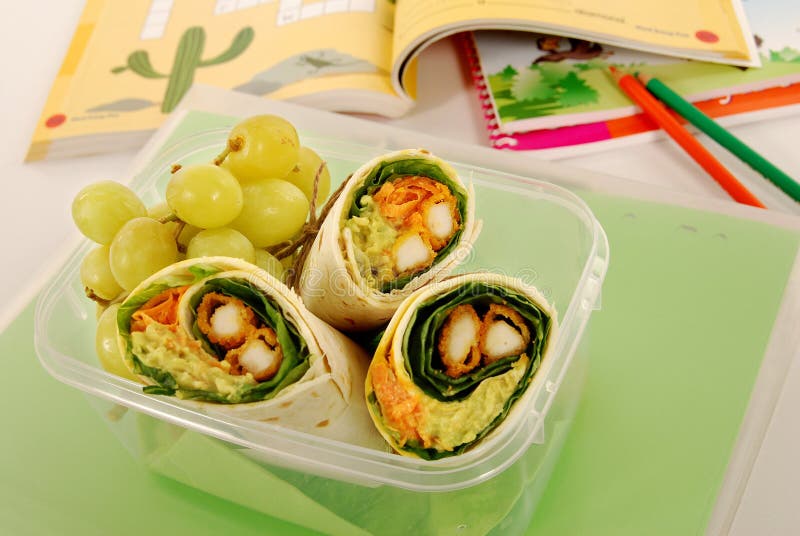 Schulmahlzeit: Hühnerverpackungssandwich im Plastikkasten mit Büchern auf Schulbank lizenzfreie stockbilder Schulmahlzeit: Hühnerverpackungssandwich im Plastikkasten mit Büchern auf Schulbank lizenzfreie stockbilder