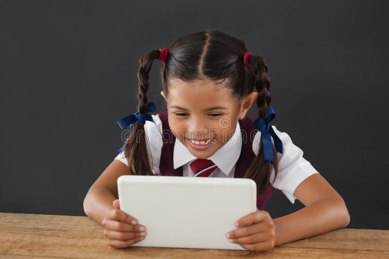 Schulmädchen, das digitale Tablette gegen Tafel verwendet