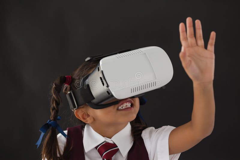 Schulmädchen, das Kopfhörer der virtuellen Realität gegen Tafel verwendet