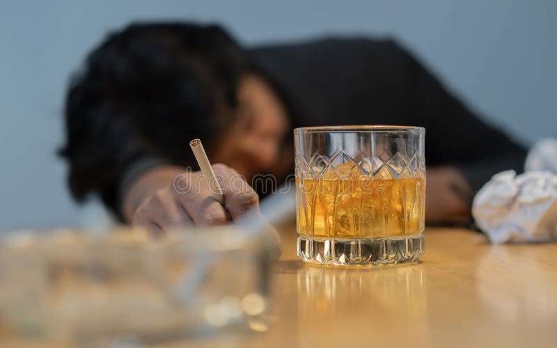 Shot of Businessman failing, serious and drink whiskey and smoke at desk in office. Selective focus on subject. Shot of Businessman failing, serious and drink whiskey and smoke at desk in office. Selective focus on subject