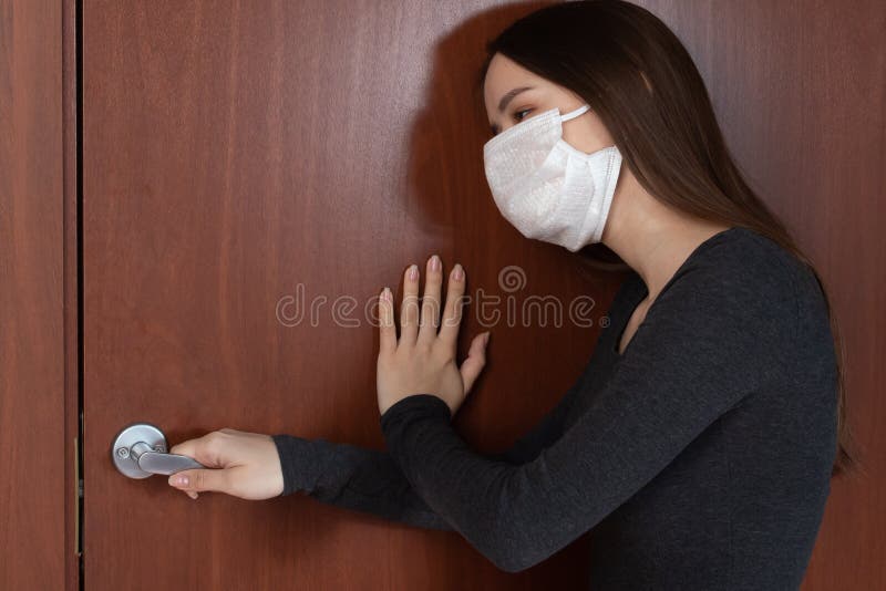 Schutz gegen die Verbreitung von Coronavirus. eine junge Frau in einer antibakteriellen Maske klopft an einer verschlossenen Tür m