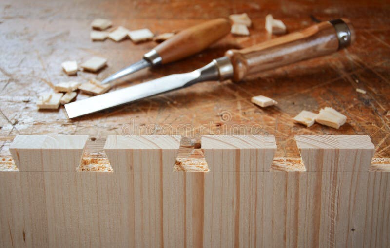 Dovetail joint on working table. Chisel and wood chips. Detail of wood joinery in spruce wood. Picture taken in woodworking workshop. Detail of wood joint. Furniture workshop. Dovetail joint on working table. Chisel and wood chips. Detail of wood joinery in spruce wood. Picture taken in woodworking workshop. Detail of wood joint. Furniture workshop.