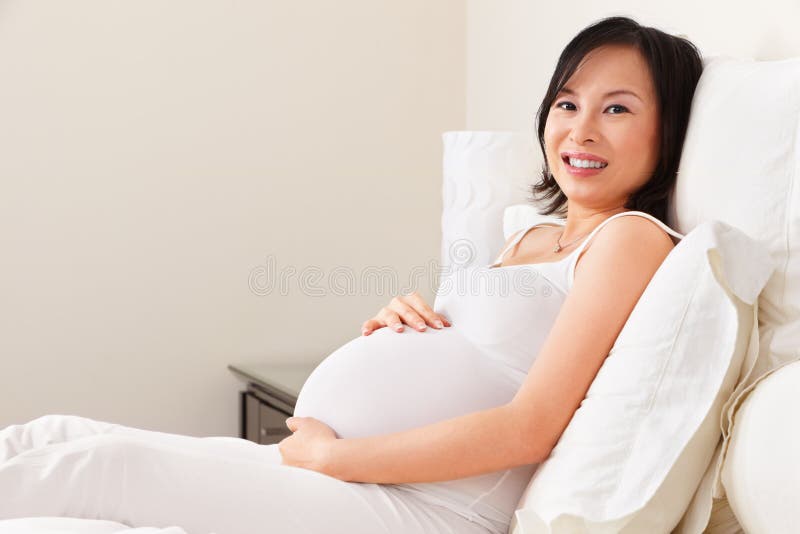 Schwangere Dame, die auf Bett stillsteht lizenzfreies stockbild Schwangere Dame, die auf Bett stillsteht lizenzfreies stockbild
