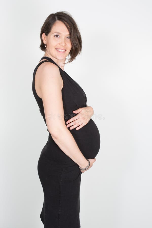 schwangere Frau der hübschen Sitzschönheit im schwarzen Kleid lizenzfreies stockfoto schwangere Frau der hübschen Sitzschönheit im schwarzen Kleid lizenzfreies stockfoto